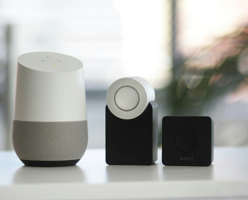 white and gray Google smart speaker and wo black speakers